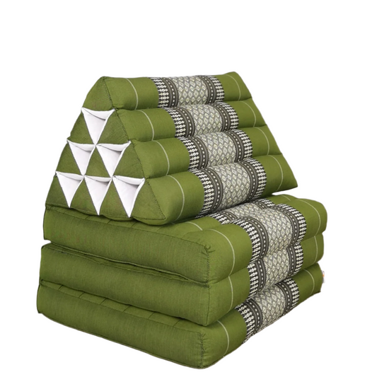 Green and patterned wedge-shaped cushions stacked on a wooden floor against a gray wall.