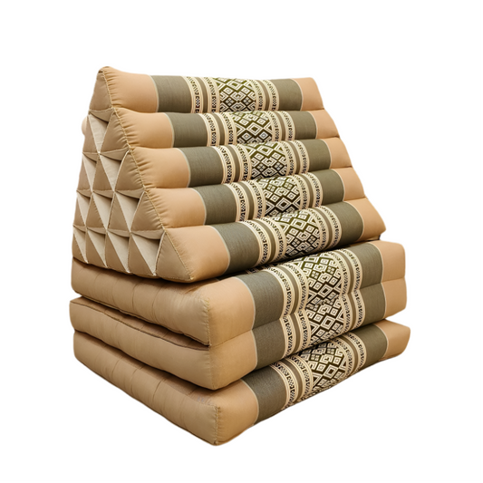 Stack of patterned cushions on a wooden floor with a neutral wall and plant in the background
